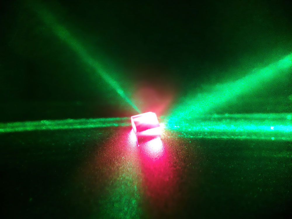 窒素–空孔（NV）欠陥中心を含むダイヤモンドに、緑色レーザー光（波長532nm）を照射したところ。赤色の光はNV中心の蛍光に起因する。
