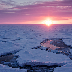 割れた海氷の向こうに沈む夕日。