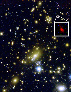 銀河団MACS J1149+2223の合成画像。強力な重力レンズ効果により、はるか遠方の銀河も拡大して観測することができる（白枠内）。