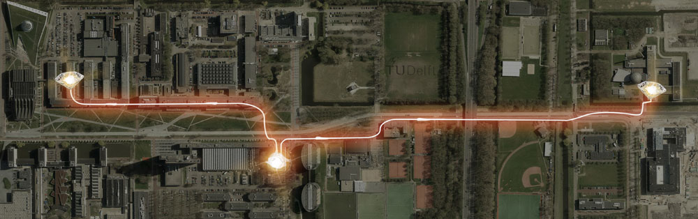 実験が行われたデルフト工科大学（オランダ）のキャンパス。両端のダイヤモンドはそれぞれ電子スピンの場所、中央やや左下は観測点、それぞれをつなぐ光線は電子間の光子の通り道を示す。電子スピン間の距離は1.3 km。