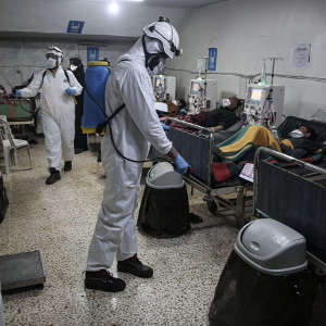 Members of the Syrian Civil Defence, also known as the White Helmets, spray disinfectant in an Idlib hospital.