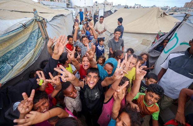 صِبيةٌ فلسطينيون يحتفلون بقرار وقف إطلاق النار في مخيم النصيرات وسط قطاع غزة.